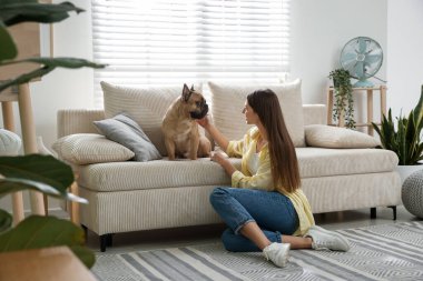 Evdeki kanepenin yanında tatlı köpeği olan bir kadın.