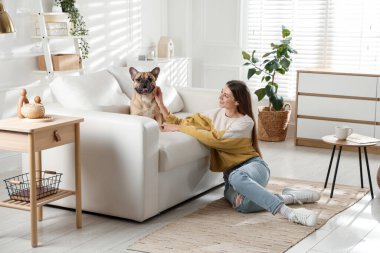 Evdeki kanepenin yanında tatlı köpeği olan bir kadın.