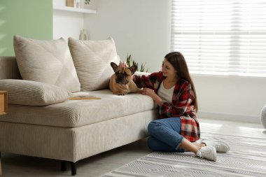 Evdeki kanepenin yanında sevimli köpeği olan bir kadın.