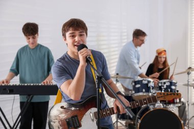 Genç müzik grubu içeride performanslarını prova ediyor.