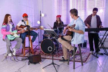 Gençlik bandosu içeride müzik öğretmeniyle performans çalışması yapıyor.