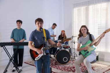 Genç müzik grubu içeride performanslarını prova ediyor.