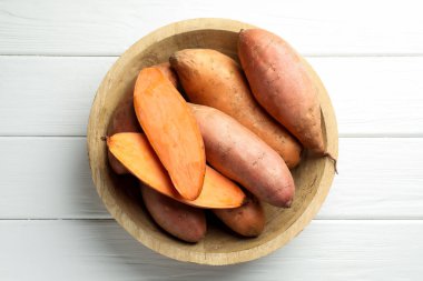 Beyaz ahşap masadaki kasede çiğ patates, üst manzara.