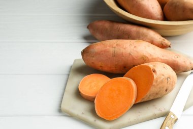 Çiğ patates ve bıçak beyaz ahşap masada, yakın plan. Metin için boşluk