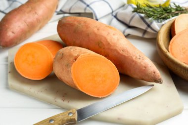 Çiğ patates ve bıçak beyaz ahşap masada, yakın plan.