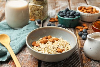 Yulaf gevreği, fındık, badem sütü ve yaban mersini ahşap masada, yakın plan.