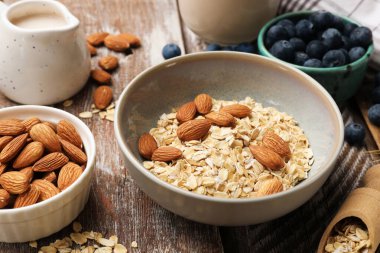 Yulaf gevreği, fındık, badem sütü ve yaban mersini ahşap masada, yakın plan.