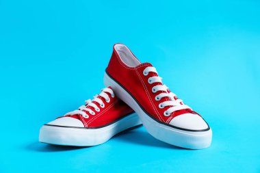 Açık mavi arka planda şık bir çift spor ayakkabı, yakın plan.