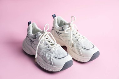 Pembe arka planda şık bir çift spor ayakkabı, yakın plan.