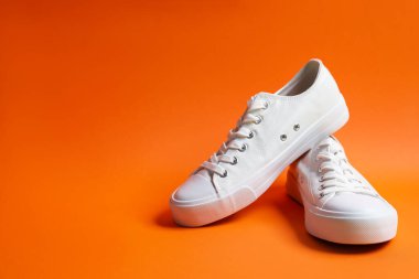 Turuncu arka planda şık bir çift spor ayakkabı, yakın plan. Metin için boşluk