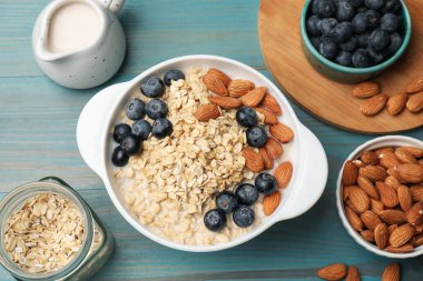 Badem sütlü, fındıklı ve yaban mersinli leziz yulaf ezmesi açık mavi ahşap masa, düz uzanmış