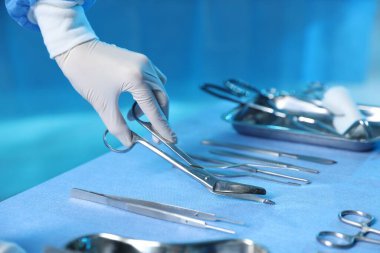 Hastanedeki masada farklı cerrahi aletleri olan doktor, yakın plan.