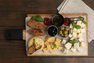 Tahtada değişik peynir, zeytin, ekmek, yağ ve fesleğen var.