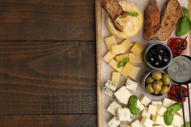 Farklı peynir, zeytin, ekmek, yağ ve fesleğen içeren servis masası, üst manzara. Metin için boşluk