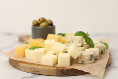 Açık mermer masada değişik peynir, zeytin ve fesleğen içeren servis panosu, yakın plan.