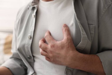 Kalp krizi geçirdi. Kapalı alanda göğüs ağrısı çeken adam, yakın plan.