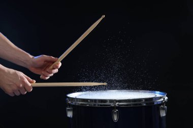 Siyah arkaplanda davul çalan bagetli adam, yakın plan