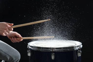 Siyah arkaplanda davul çalan bagetli adam, yakın plan