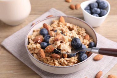 Bademli yulaf gevreği, yaban mersini ve süt ahşap masada, yakın plan.