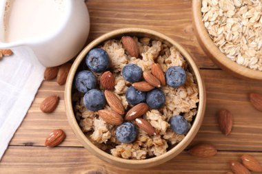 Yulaf gevreği, badem sütü, fındık ve yaban mersini ahşap masada, düz uzanmış.