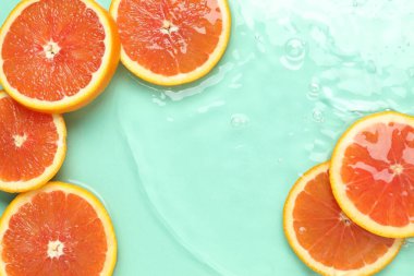 Turkuaz arka planda greyfurt dilimleri, düz bir zemin. Metin için boşluk