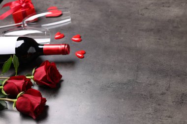 Güzel güller, kadehli şarap ve gri arka planda dekoratif kalpler, yakın plan. Metin için boşluk