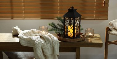 Noel feneri, yanan mumlar ve kapalı bir bankta kazak. Sıcak atmosfer