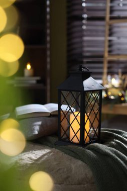 Kapalı alanda yanan mum ve battaniyeli Noel feneri. Bokeh etkisi
