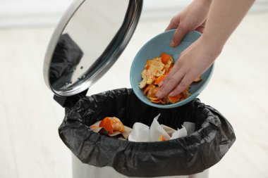 Mutfaktaki çöp kutusuna mandalina kabuğu atan kadın, yakın plan.