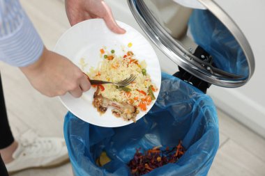 Mutfaktaki çöp kutusuna yemek atan kadın, yakın plan.