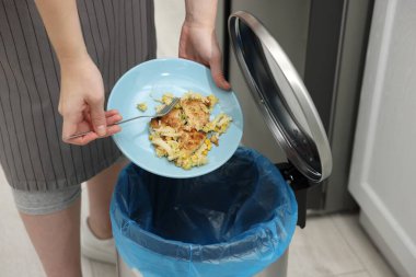 Mutfaktaki çöp kutusuna yemek atan kadın, yakın plan.
