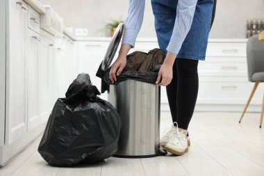 Mutfaktaki çöp kutusuna plastik poşet koyan kadın, yakın plan.
