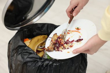 Mutfaktaki çöp kutusuna yemek atan kadın, yakın plan.