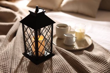 Güzel bir Noel feneri, yanan mumlar ve sıcak bir bardak içecekle kapalı bir yerde, yakın plan.