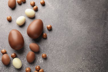 Paskalya kutlaması. Gri desenli masa üzerinde bir sürü çikolata yumurtası ve dragee, metin için boşluk ile düz yatıyordu.