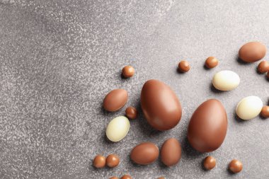 Paskalya kutlaması. Gri desenli masa üzerinde bir sürü çikolata yumurtası ve dragee, metin için boşluk ile düz yatıyordu.
