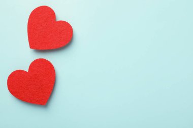 Sevgi. Açık mavi arka planda kırmızı dekoratif kalpler, düz yatış. Metin için boşluk