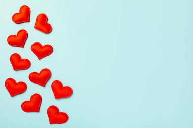 Sevgi. Açık mavi arka planda kırmızı dekoratif kalpler, düz yatış. Metin için boşluk