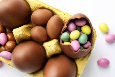 Çikolatalı Paskalya yumurtası ve beyaz arka planda karton şekerler.