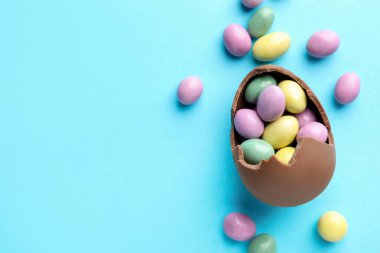 Paskalya kutlaması. Açık mavi arka planda şekerli kırık çikolata yumurtası, düz. Metin için boşluk