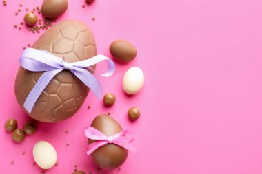 Pembe arka planda şekerli, çikolatalı Paskalya yumurtaları. Metin için boşluk