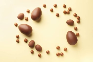 Bej arka planda çikolatalı Paskalya yumurtaları ve şekerler, düz konum. Metin için boşluk