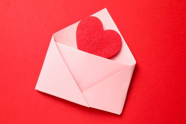 Sevgi. Kırmızı arkaplanda dekoratif kalpli zarf, üst görünüm