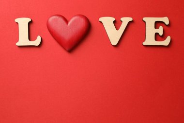 Aşk kelimesi ahşap harflerden ve kırmızı arka planda dekoratif kalpten yapılmıştır. Metin için boşluk