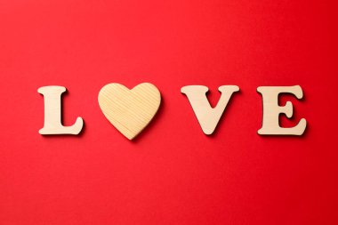 Aşk kelimesi ahşap harflerden ve kırmızı arka planda dekoratif kalpten yapılmıştır.