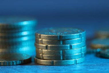 Stacks of coins on wooden table against blurred background, closeup