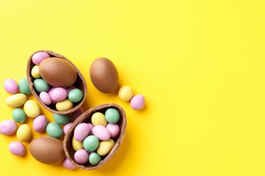 Mutlu Paskalyalar. Sarı arka planda renkli şekerlemeli leziz çikolatalı yumurtalar. Metin için boşluk