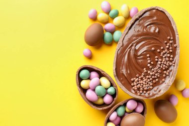 Mutlu Paskalyalar. Sarı arka planda renkli şekerlemeli leziz çikolatalı yumurtalar. Metin için boşluk