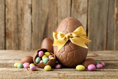 Ahşap masada renkli şekerlemeli lezzetli çikolata yumurtaları, yakın plan. Mutlu Paskalyalar