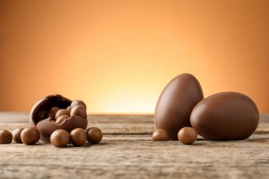 Ahşap masadaki çikolatalı yumurtalar, renkli arka plana karşı, yakın plan. Mutlu Paskalyalar